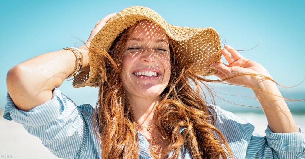 Beautiful woman wearing a sun hat smiling with her eyes closed (model)