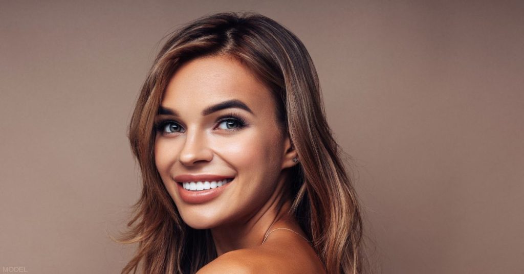 Woman with beautiful eyebrows looking over her shoulder and smiling (model)