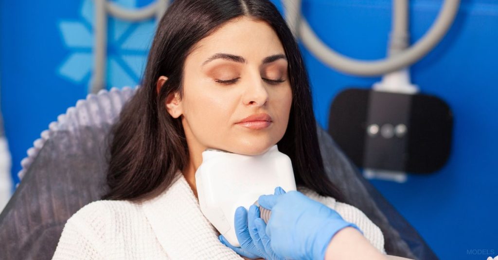 Woman receiving a CoolSculpting® treatment on her chin (models)