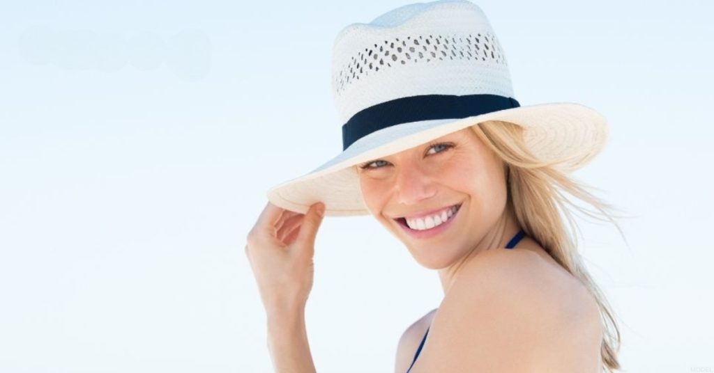 A woman wearing a hat on the beach (model)